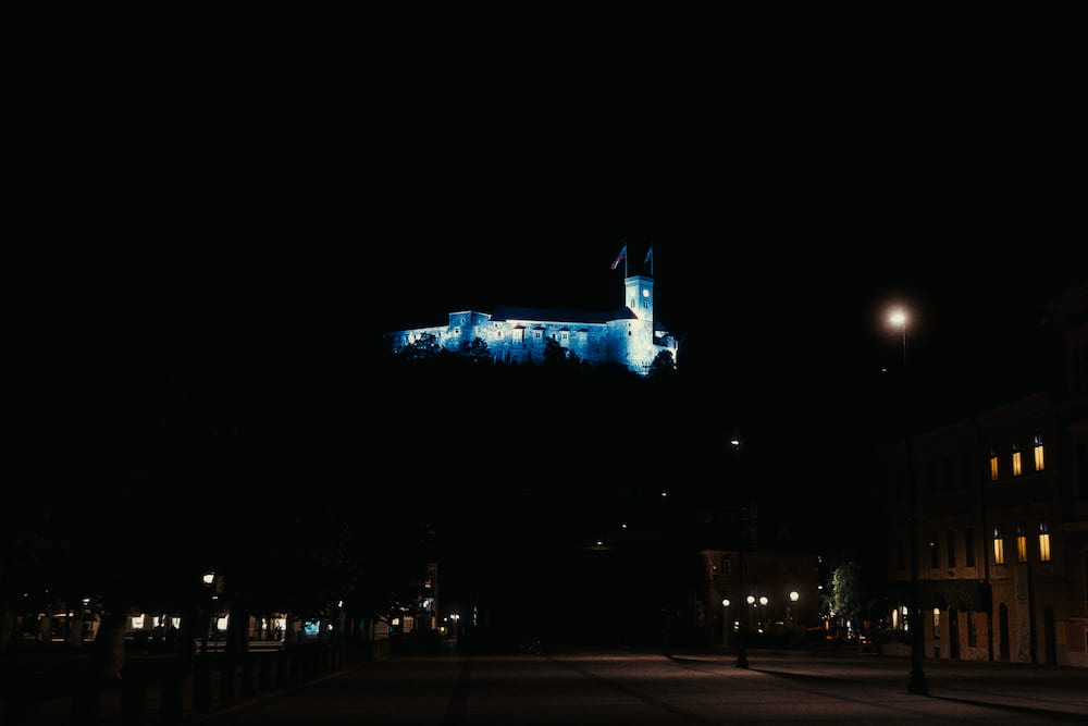 The castle lit blue far off on its hill, a dark square below