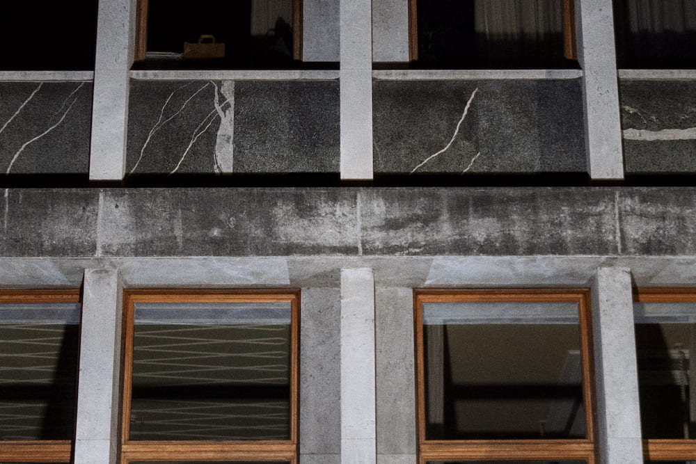 A concrete and marble facade with wooden window frames, close up