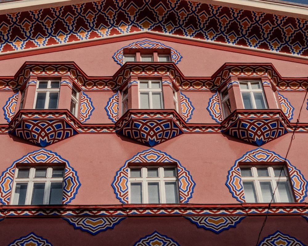 A pink facade painted with blue and red patterns around its windows