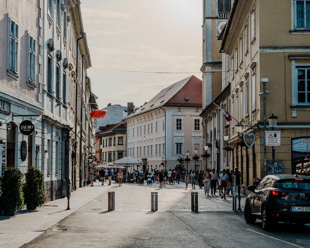 A narrow old town street with bollards, people at the far end, a parked car
