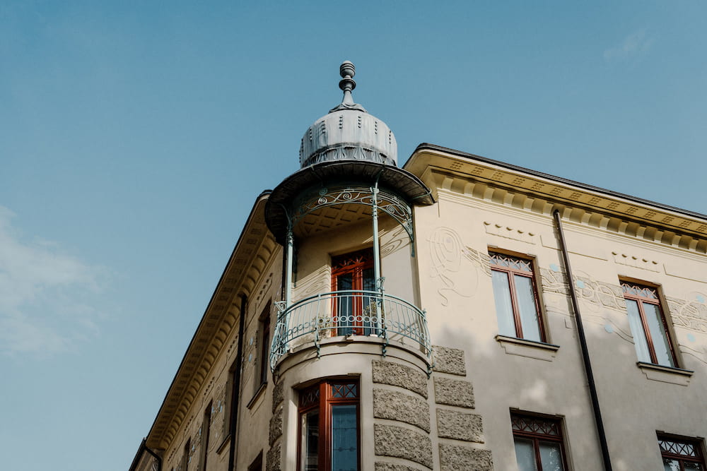 A corner building with a round balcony tower and a small dome against blue sky