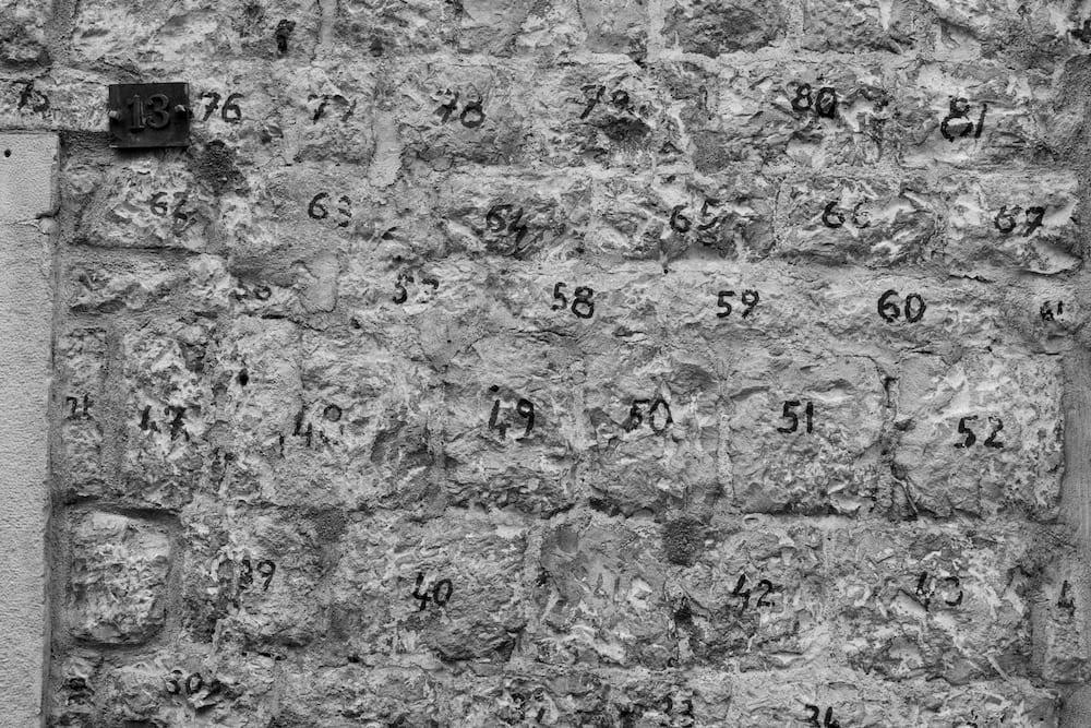 Black and white: a stone wall with a number painted on each stone.