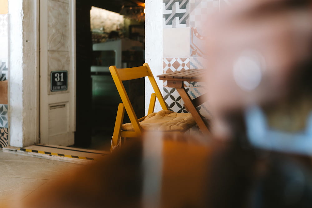 A yellow folding chair in a doorway, something out of focus in front.