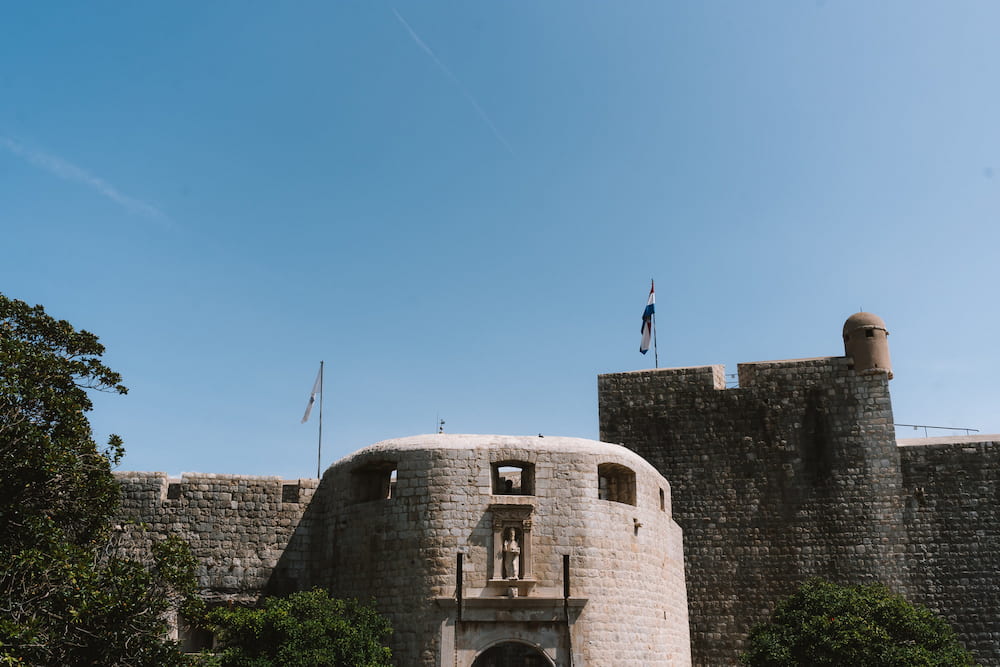 A round stone fortress with a flag under a blue sky.