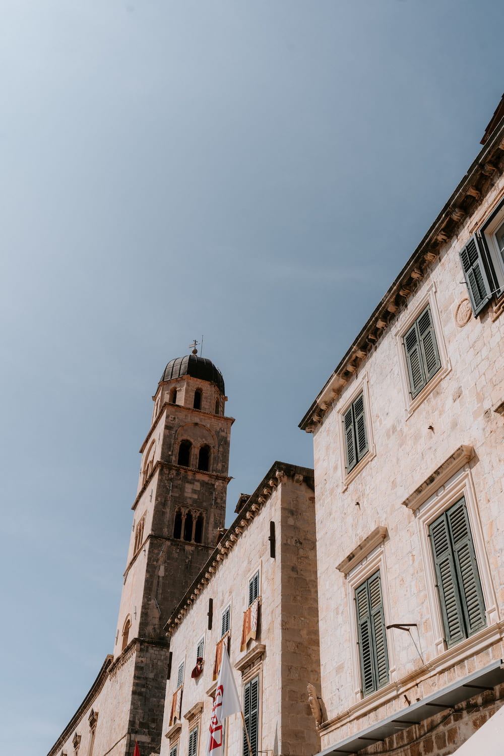 A bell tower at the end of a row of stone houses, seen from below.
