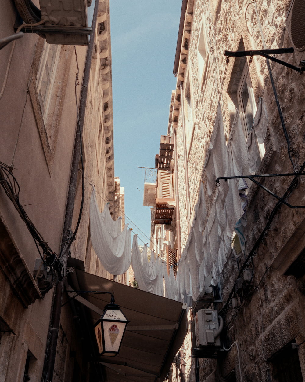 White sheets hung across a narrow lane between stone walls, a lantern.