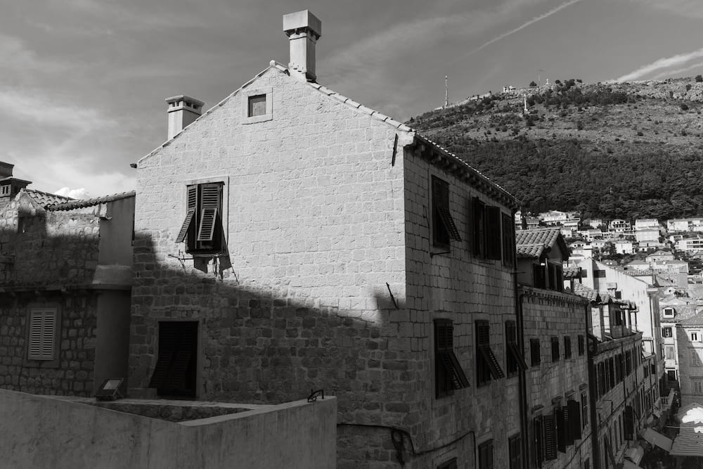 Black and white: a stone house on a hill above roofs.