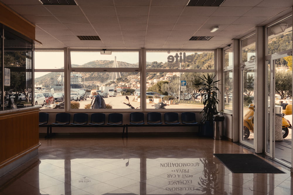 A bright waiting hall with big windows onto a harbour.