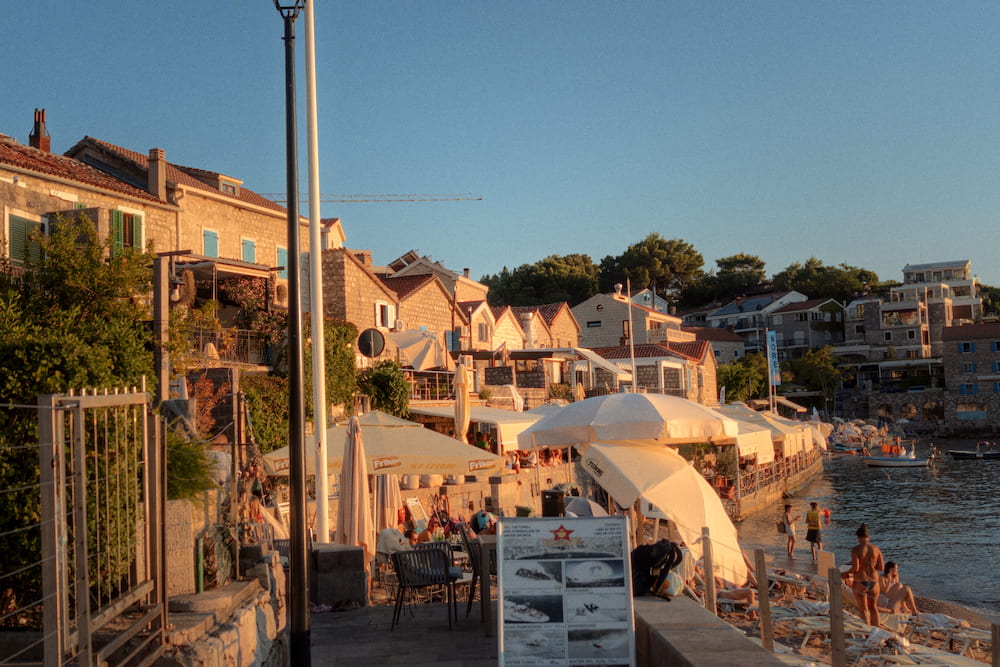 Houses and parasols along the shore in evening light