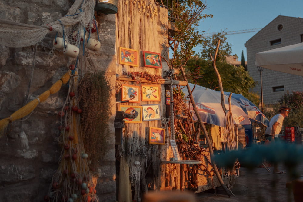 Fishing nets, floats and painted tiles hung on a stone wall in low sun