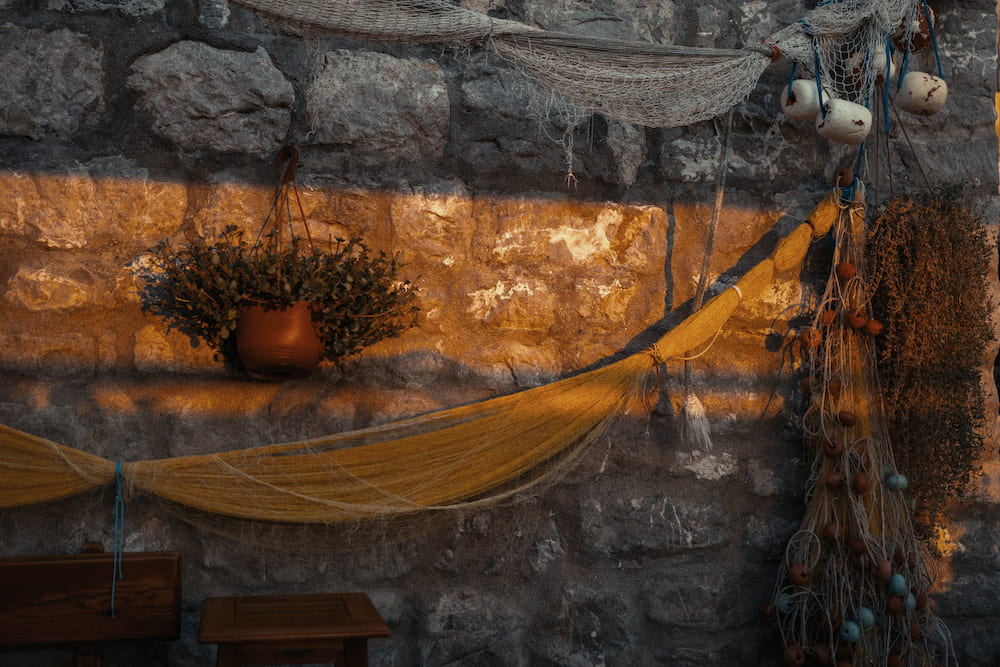 A yellow net slung across a stone wall, a pot of flowers above it