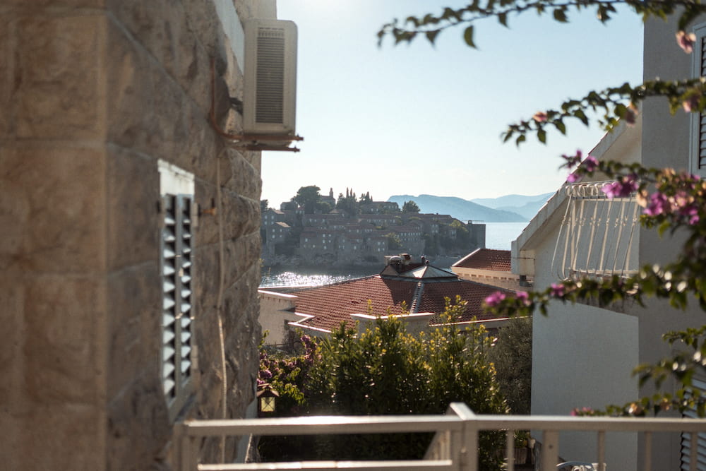 A stone house and bougainvillea, the island of Sveti Stefan across the water