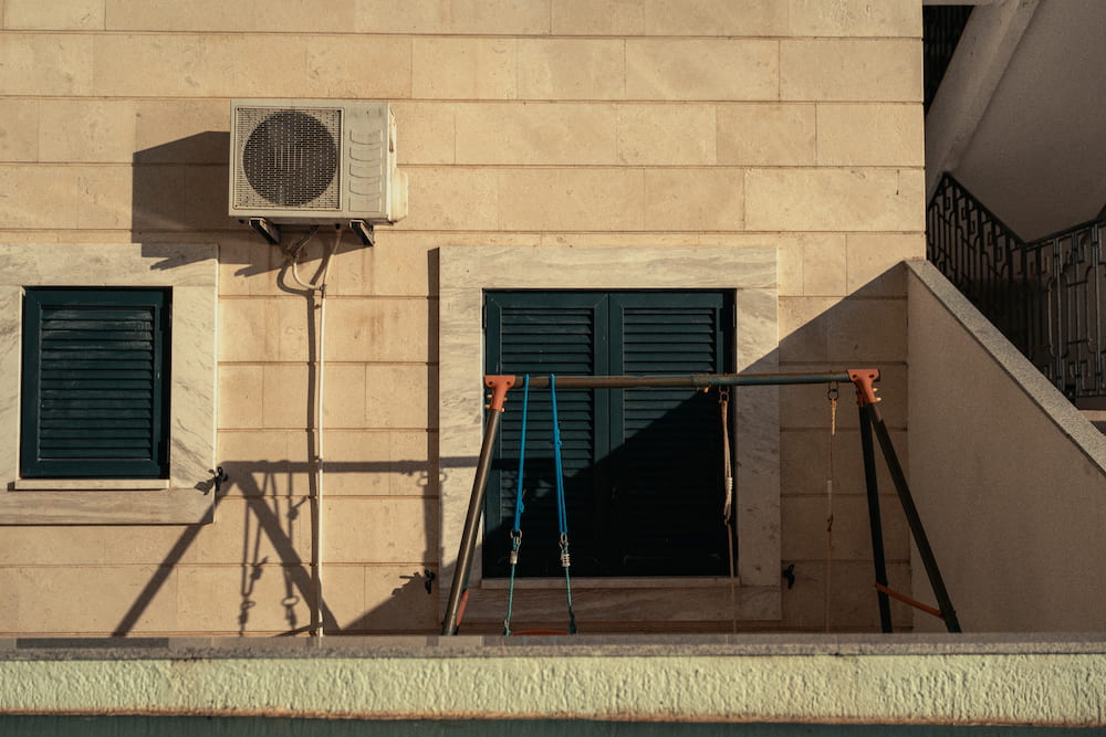 A cream wall with green shutters and a rusty frame in front