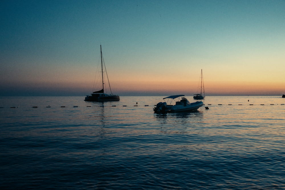 The same boats at anchor in colour, the sky turning orange