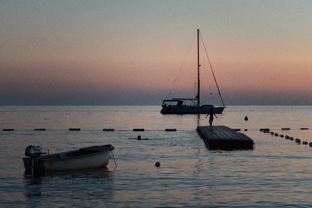 A sailing boat, a raft and a dinghy at dusk