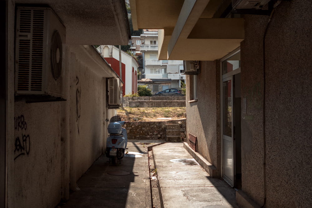A narrow alley between buildings, a scooter at the end