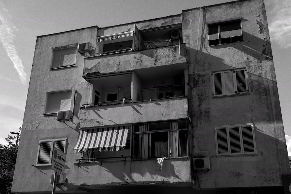 Black and white: a weathered apartment block with balconies and awnings