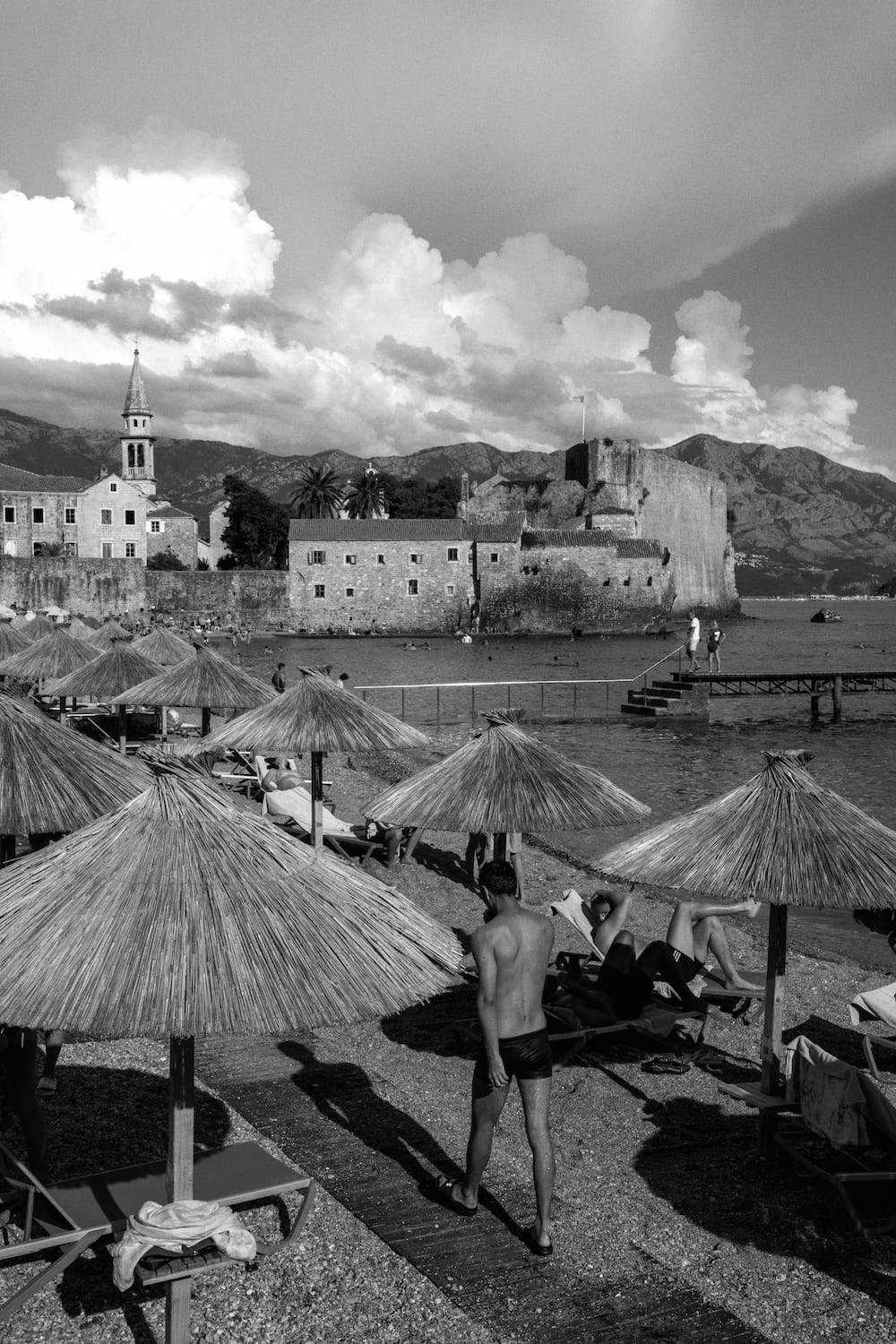 Black and white: thatched parasols on a beach below the old town