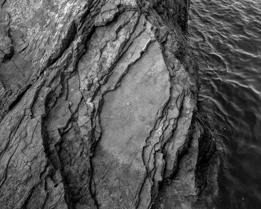 Black and white: layered rock at the water's edge