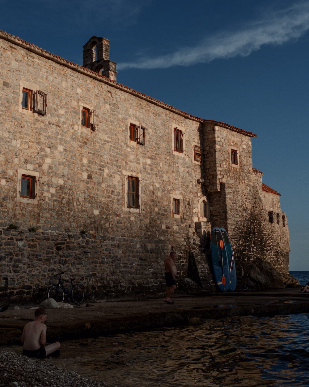 The stone building from its corner, a swimmer in front