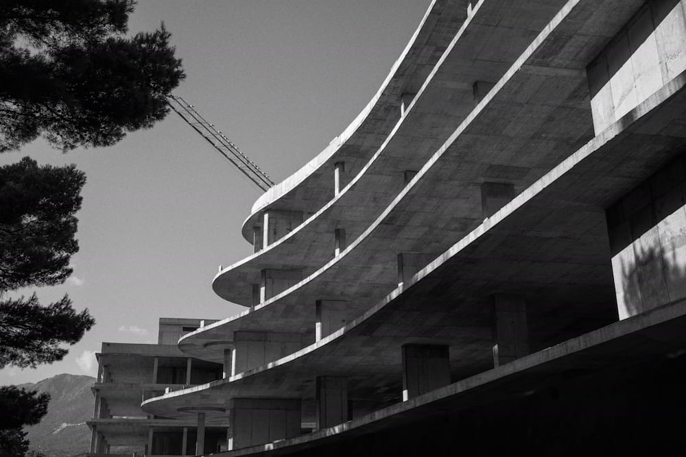 Black and white: the unfinished building and a crane behind pines