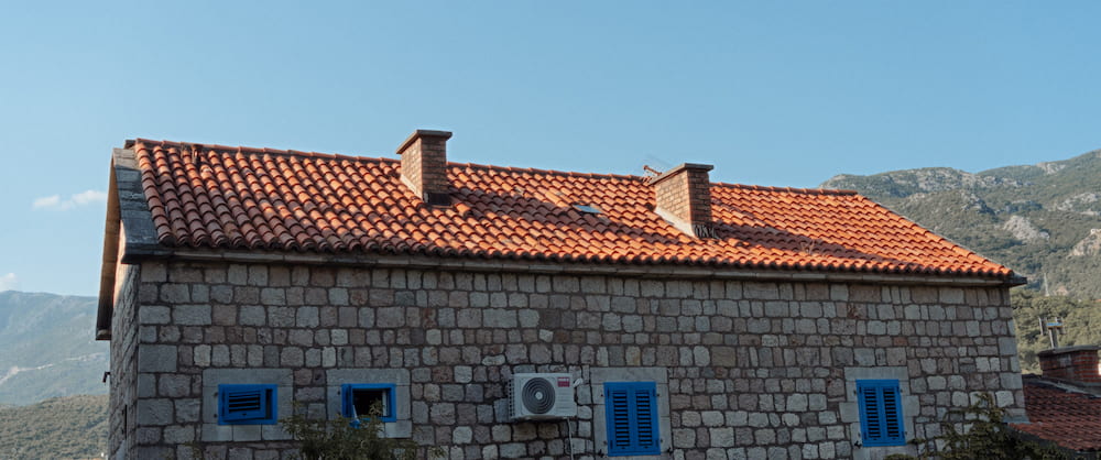 A stone house with blue shutters and a tiled roof