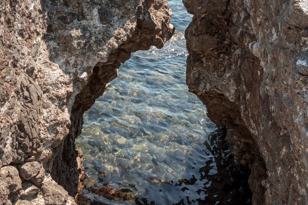 Clear water seen through an arch in the rock
