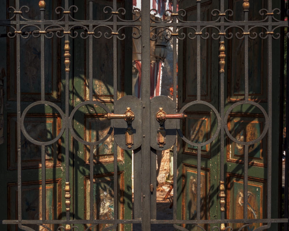 An ornate iron gate in front of a dark doorway