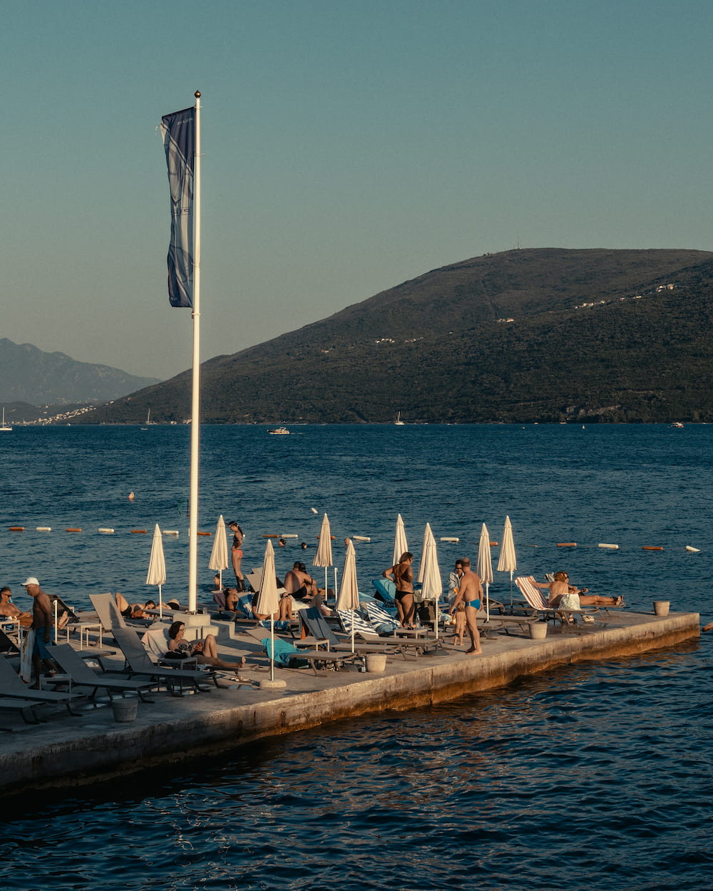 A flag over a bathing platform, hills across the bay