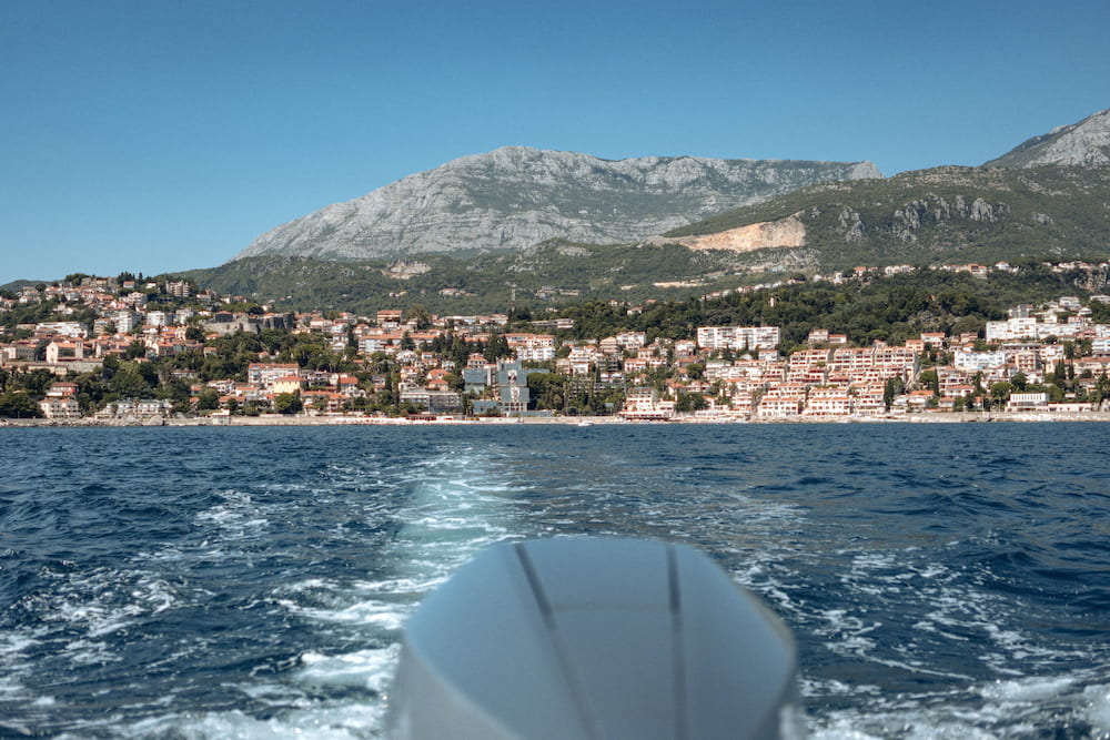 The wake of a boat, a town on the hill behind
