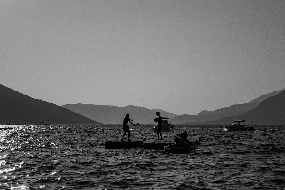 Black and white: paddle boarders on the bay, mountains behind