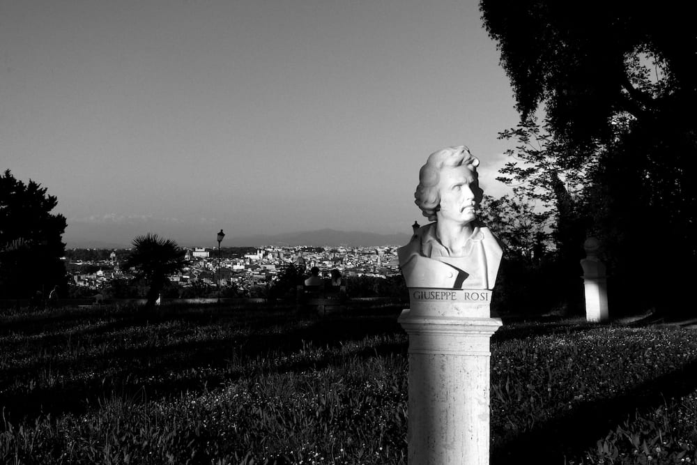 Black and white: a marble bust on a hill, the city below.
