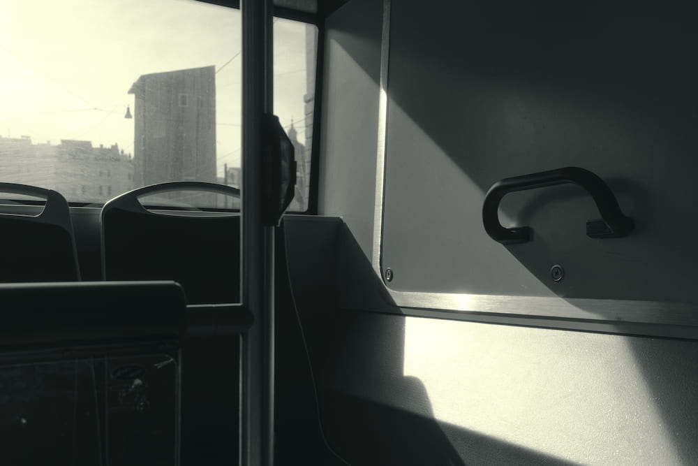 Inside a bus: seats, a window and a handle in the sun.