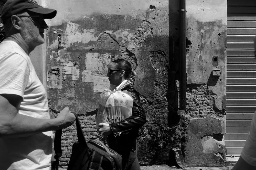 Black and white: two men talking in front of a weathered wall.
