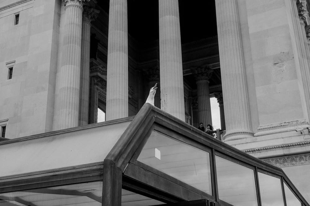 Black and white: the columns of a portico over a glass canopy.