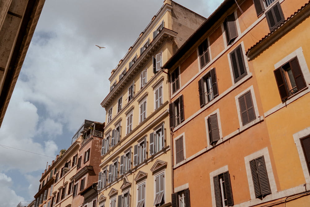 Ochre and pink apartment blocks from below, a cloudy sky.