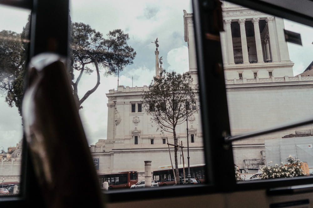A white marble monument seen through the window frame of a bus.